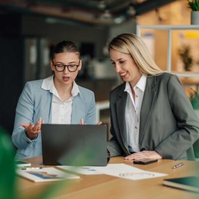 Two businesswomen collaborating while analyzing data on a laptop