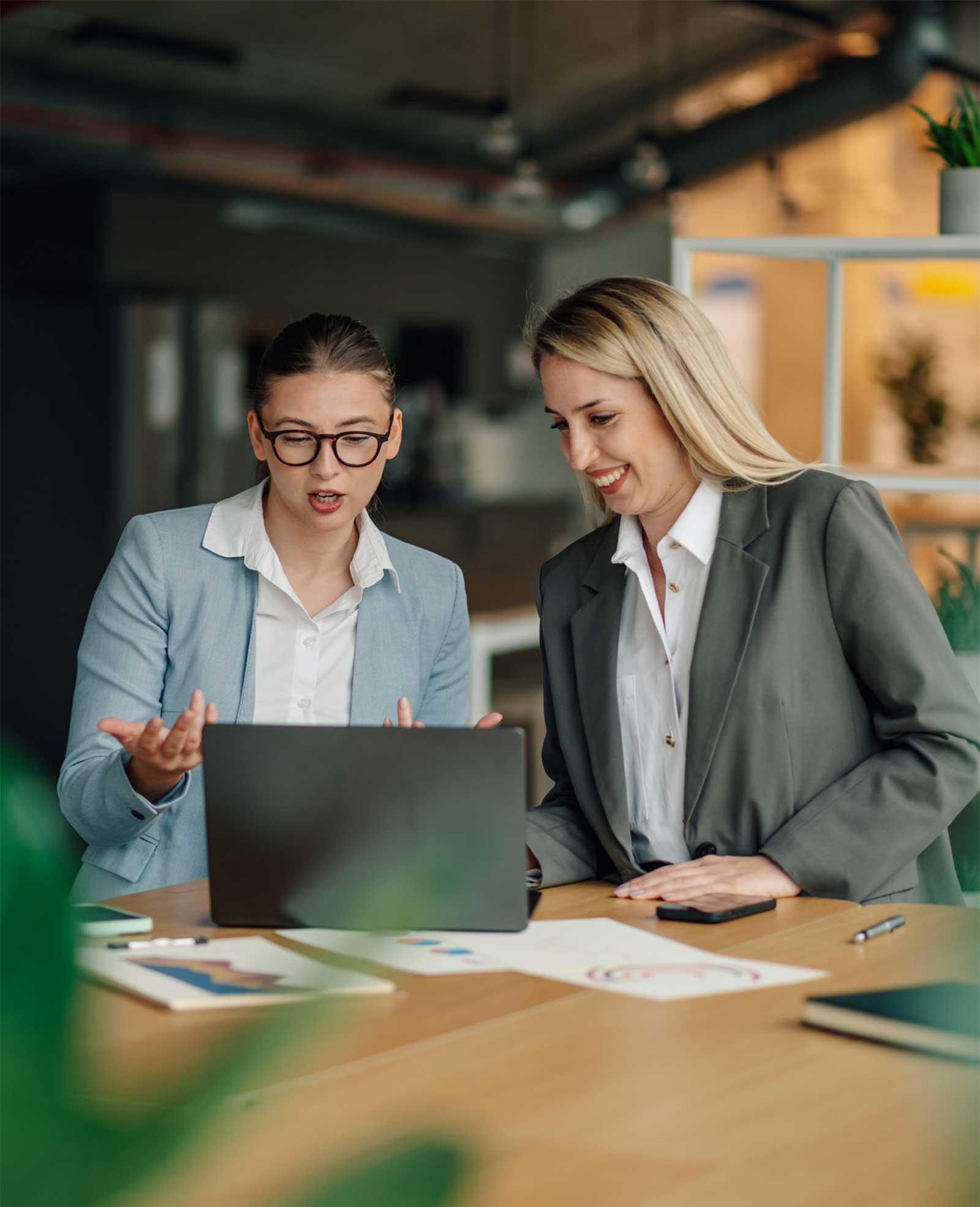 Two businesswomen collaborating while analyzing data on a laptop